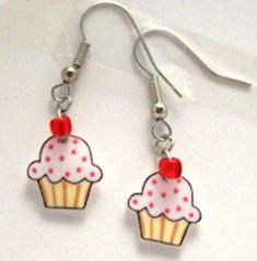 two cupcakes with cherries on them are hanging from silver ear wires