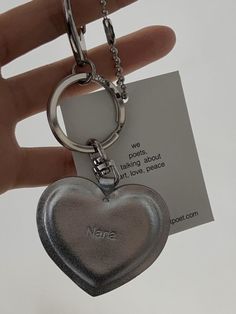 a heart shaped keychain is being held by a hand with a note attached to it