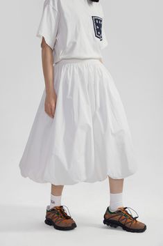 Elevate your wardrobe with this High-Waisted Pleated Slip Midi Skirt – a timeless piece blending a touch of retro charm with modern sophistication. Meticulously crafted from 100% cotton, this skirt features an array of finely tailored pleats that create a voluminous silhouette, enhancing its graceful movement. The solid color and subtle texture offer a versatile base for an array of styling options. A natural waistline and A-line cut promote a flattering fit, while practical side pockets bring a Voluminous Skirt Outfit, Ballon Skirts, Sporty Skirt Outfits, Midi Skirt Sneakers, Balloon Skirt Outfit, Slip Midi Skirt, Pleated Skirt Outfit, Asymmetrical Midi Skirt, Pleats Skirt