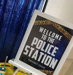 a police station sign sitting on top of a desk next to a toy car and a blue curtain