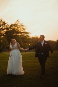 a bride and groom hold hands as the sun sets in the background at their wedding