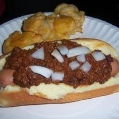 a paper plate with a chili dog and potatoes on it, ready to be eaten