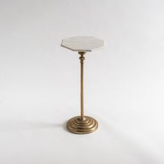 a white marble topped table on a gold metal stand against a white background with the top off