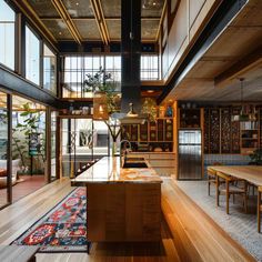 an open kitchen and dining area with wood floors, windows, and wooden table tops