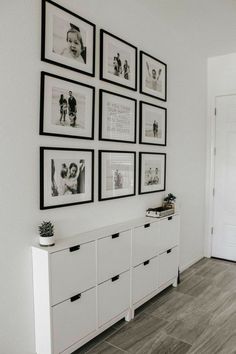 a white room with pictures on the wall and drawers in front of an open door