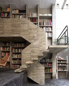 the stairs are made out of concrete and have bookshelves on each side, along with shelves full of books