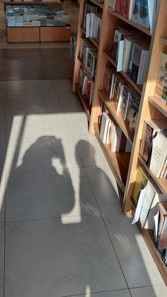 the shadow of a person standing in front of bookshelves