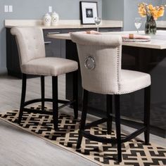 two beige barstools sitting on top of a rug in front of a counter