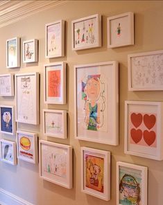 there are many framed pictures on the wall in this room, including children's drawings