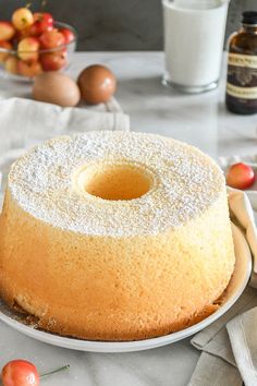 a cake sitting on top of a white plate covered in powdered sugar and cherries