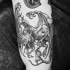 a black and white photo of a tattoo on someone's arm with a dragon