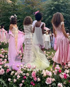 several women in dresses are walking through a flower filled field with pink and white flowers