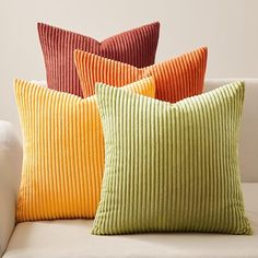 four different colored pillows sitting on top of a white couch