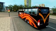 a black and orange bus driving down a street next to a tall building on a sunny day