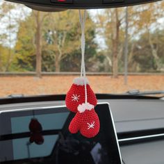 a pair of red mittens hanging from the dashboard of a car