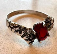 Embrace the allure of the night with this stunning vintage gothic ruby ring. Crafted from sterling silver, this intricate vintage piece features a vibrant ruby, a gemstone associated with passion, energy, and courage. Its deep crimson hue perfectly complements the ring's gothic design, making it a captivating statement piece. Whether you're attending a masquerade ball or simply want to add a touch of mystery to your everyday style, this ring is the perfect choice. Keywords: vintage, gothic ring, ruby ring, sterling silver ring, dark jewelry, statement ring, handmade jewelry, unique jewelry, gothic style, gothic fashion, gemstone jewelry, ruby, crimson, passion, energy, courage. Silver Ruby Ring, Jewelry Ruby, Dark Jewelry, Gothic Ring, Jewelry Gothic, Ring Ruby, Style Gothic, Gothic Design, Signet Rings