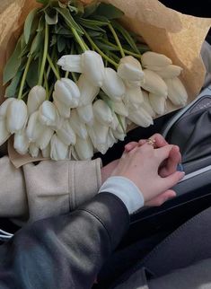 a bouquet of white tulips is being held by a woman in a car