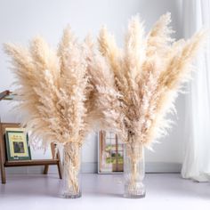 two vases filled with dried flowers on top of a table