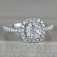 an engagement ring with a cushion cut diamond surrounded by small round diamonds on the band