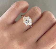 a woman's hand with a diamond ring on top of her finger and an engagement band