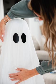 a woman is decorating a white ghost pillow