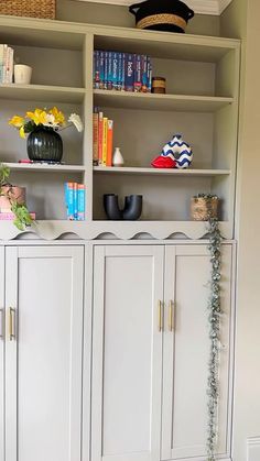 a white bookcase filled with lots of books and vases on top of it