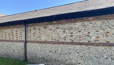 an old brick building with grass in the foreground and blue sky in the background