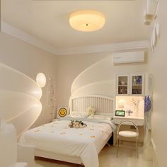 a white bed sitting in a bedroom next to a desk and chair on top of a hard wood floor