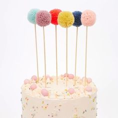 a white cake topped with frosting and colorful pom - poms