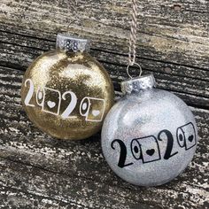 two silver and gold christmas ornaments sitting on top of a wooden table next to each other