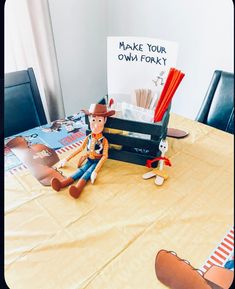 a toy cowboy sitting on top of a table next to a sign that says make your own forky