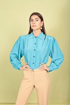 "Gorgeous blouse in an aquamarine blue color with small pointed collar, fitted pleats at the waistline, long sleeves that cuff at the wrists, black buttons from the neck down and pleats at the shoulders. Doesn't stretch and fabric has a shimmery look to it. ➽ brand: Sk & Company ➽ material: poly ➽ condition: great shape! missing the last button ➽ model stats: 32\" 24\" 35\" 5\"7 ➽ size: medium ➽ measures: waist 34\" / pit to pit 44\" / bust 42\" / length 24\" ➽ Apple Branches Vintage applebranch Elegant Luxury Light Blue Blouse, Affordable Non-stretch Blue Blouse, Luxury Light Blue Button-up Top, Luxury Light Blue Fitted Blouse, Luxury Fitted Light Blue Blouse, Luxury Light Blue Blouse Piece For Women, Affordable Blue Collared Blouse, Cheap Blue Workwear Blouse, Cheap Non-stretch Blue Blouse