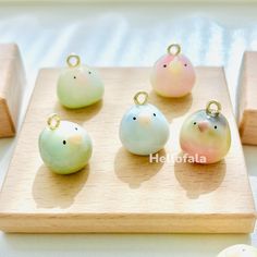 four little birds sitting on top of a wooden board next to some small ones in pastel colors