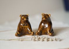 two brown bear figurines sitting next to each other on a white tablecloth