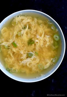 a white bowl filled with soup on top of a black countertop next to a spoon