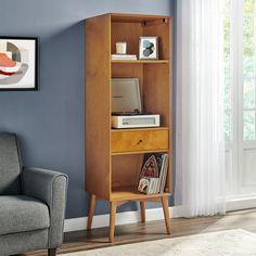 a wooden bookcase sitting next to a gray couch in a room with blue walls