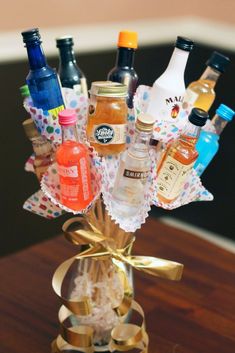 a vase filled with lots of bottles on top of a wooden table