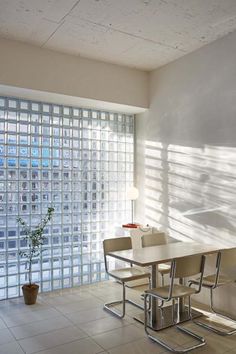 a dining room table with four chairs in front of a glass block wall and floor