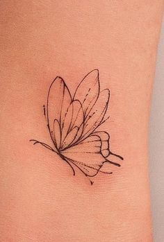 a small butterfly tattoo on the side of a woman's rib - up stomach