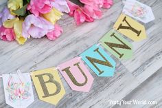 a bunting banner that says bunny on it with flowers in the background and easter decorations