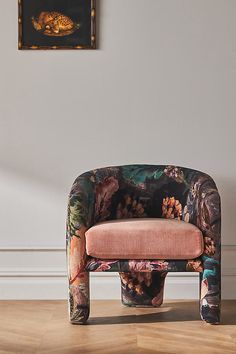 a chair with a flowered upholstered seat in front of a painting on the wall