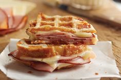 two ham and cheese waffle sandwiches sitting on top of a white paper wrapper