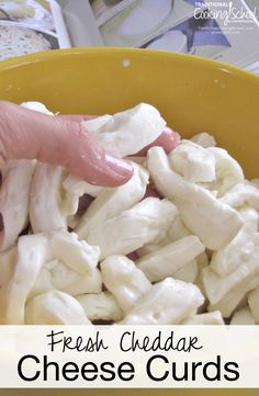 a hand picking up cheese from a yellow bowl with the words fresh cheddar cheese curls