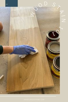 a person in blue gloves wiping down some paint on a wooden surface with wood stain