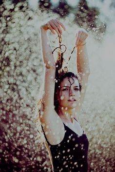 a woman standing in the rain with her arms up