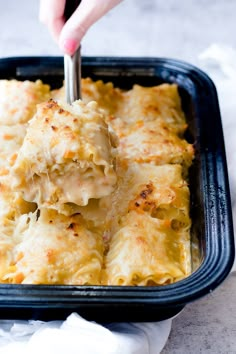 a person is spooning some food out of a casserole dish