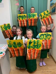 the children are holding up their carrot paintings