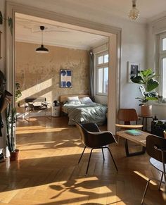 a living room filled with furniture and lots of windows next to a bed in a bedroom