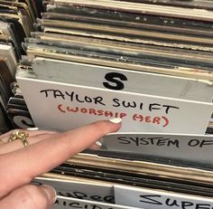 a hand pointing at a stack of records with the word taylor swift worship gear on it