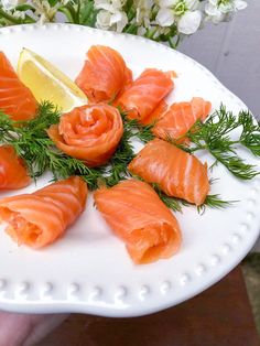 a white plate topped with lots of salmon and garnished with lemon wedges